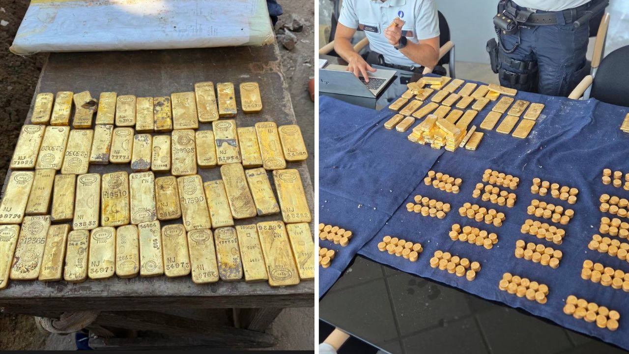 Pile of gold bars on a table, with stamped markings, next to a blue bag—likely seized gold.