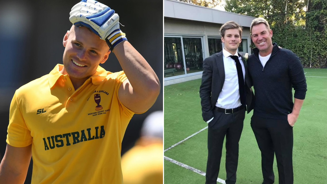 Cricketer in a yellow Australia jersey smiling and tipping his helmet on the field.