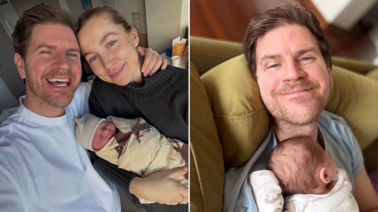 Happy couple with their newborn baby, smiling in a cozy home. Public moment of new parent joy.