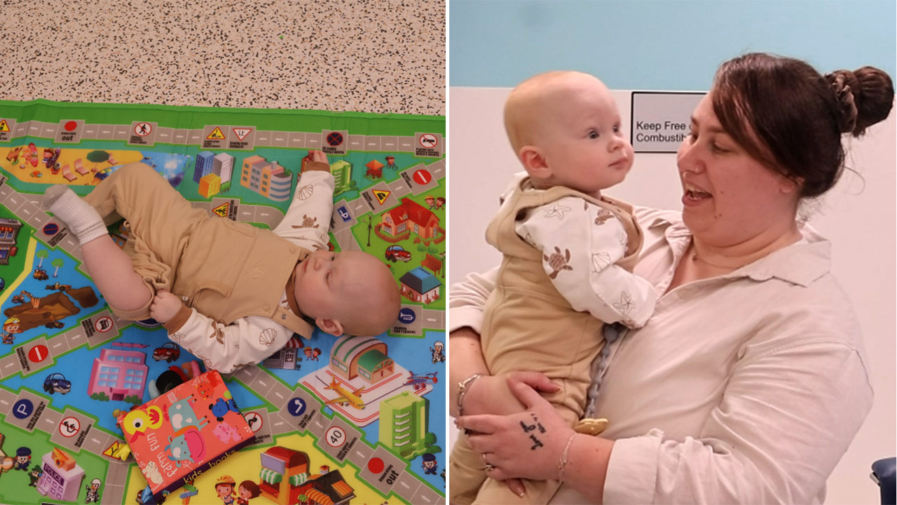 Baby lying on a colorful city-themed play mat with roads and toys on the floor, next to a book. Left panel.