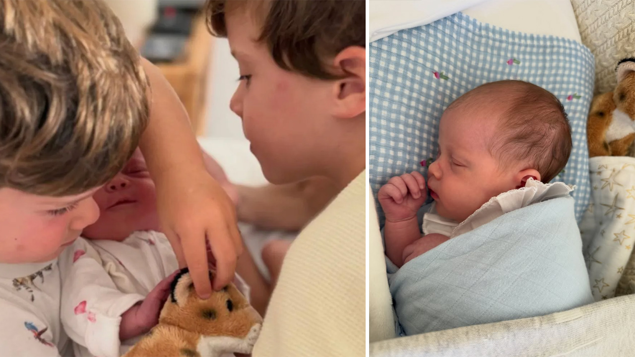 Two young children cuddle a newborn baby, with a tiger plush nearby.