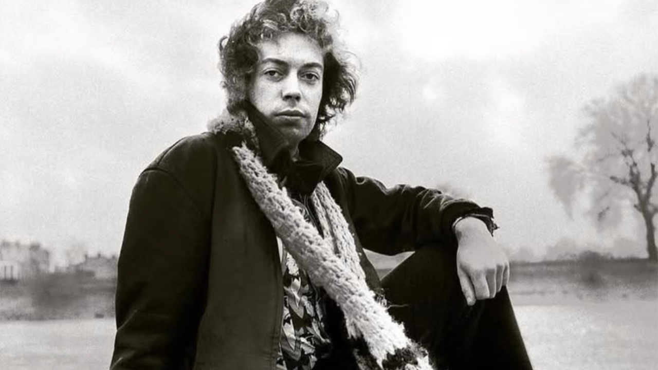 Black-and-white portrait of a young man with curly hair wearing a heavy coat and a thick scarf, outdoors in winter.