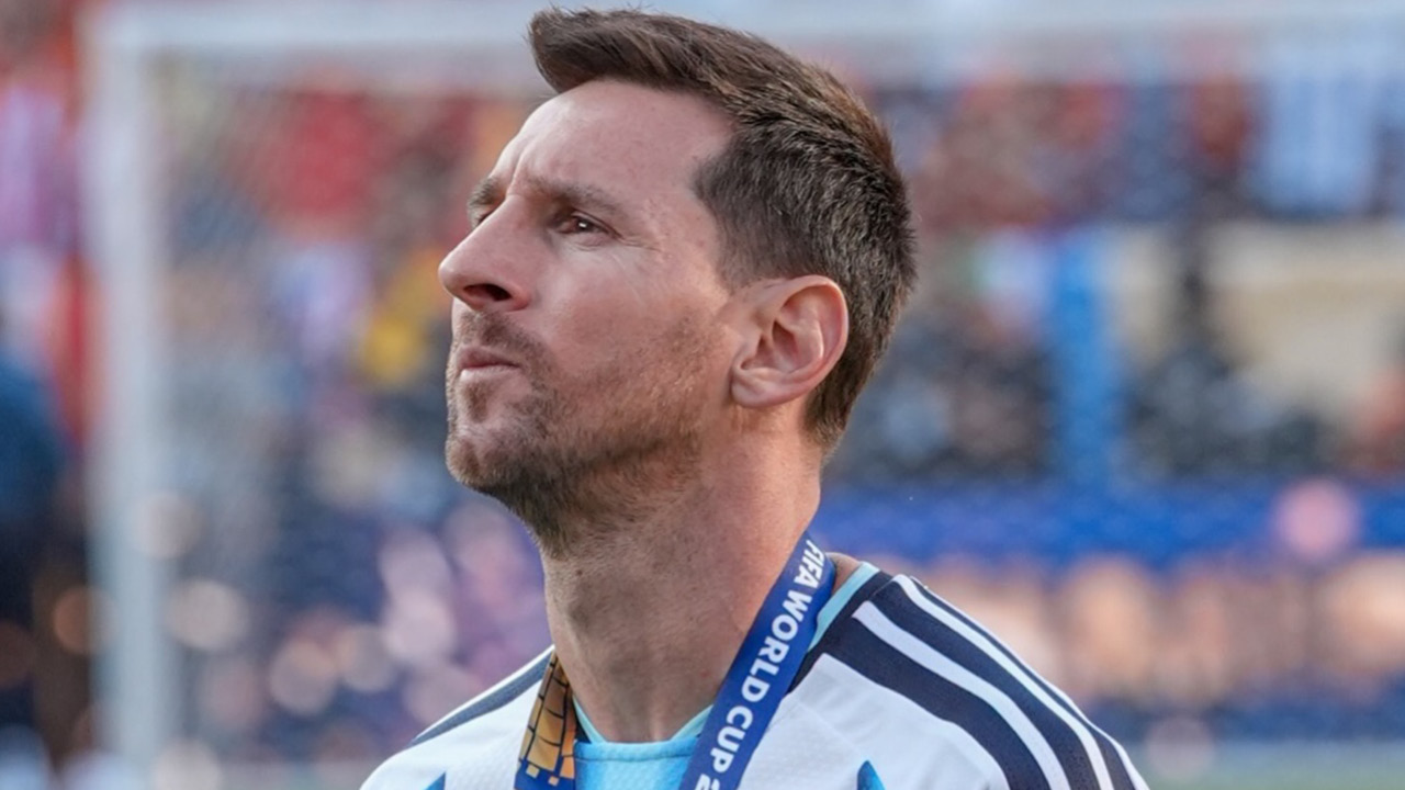 Male soccer player in a light blue and white jersey with a World Cup lanyard around the neck, gazing upward on the field.